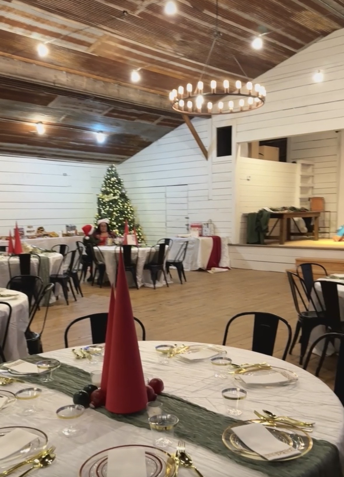 Willow Hall set up for a holiday party with round tables, Christmas tree, and stage